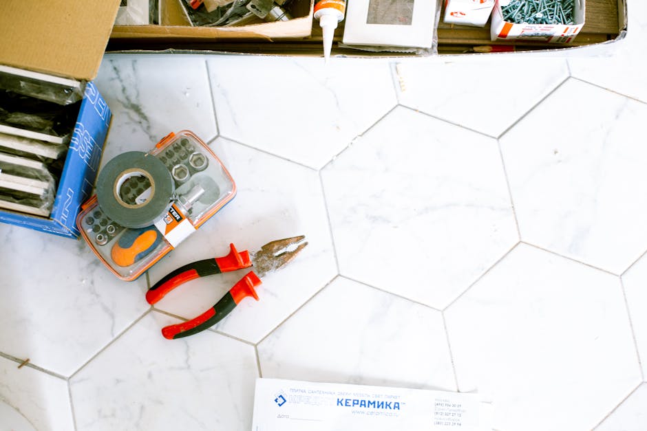 A selection of home renovation tools placed on a white tiled floor, ready for use.